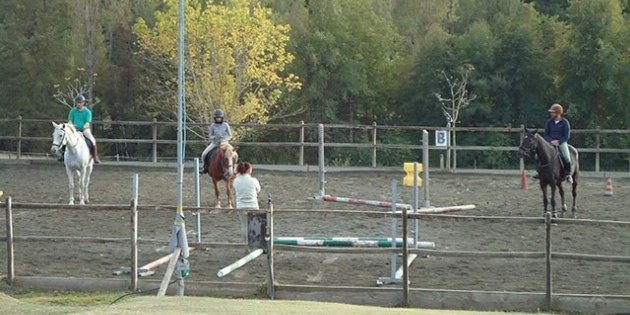 Reitplatz mit 3 Reitern und Reitlehrerin