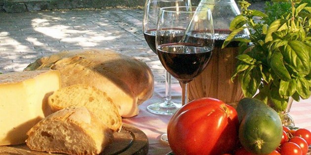 Picknick mit 2 Gläsern Rotwein, Brot, Käse, Tomaten, Gurke und Basilikum